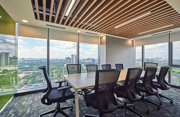 - - Modern conference room with a wooden table and black ergonomic chairs, large windows offer a cityscape view.
